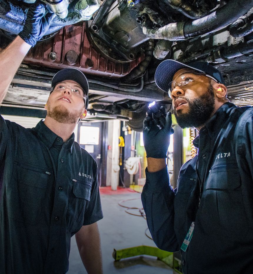 Two Delta engineers look up at an engine