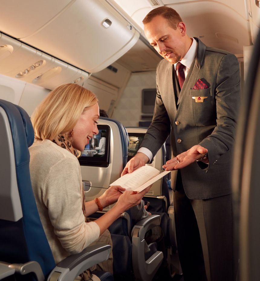 A Delta flight attendant assists a passenger on board a flight