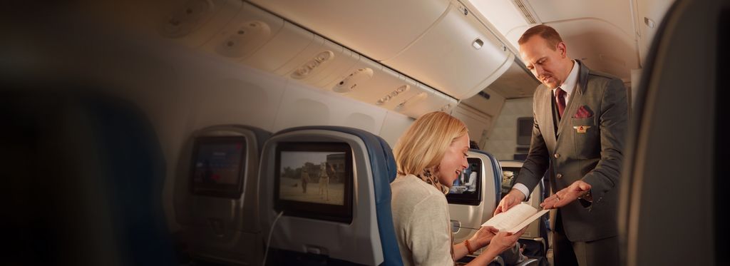 A Delta flight attendant assists a passenger on board a flight