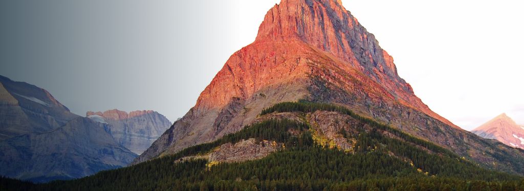 A mountain catches the orange-pink light of the sun