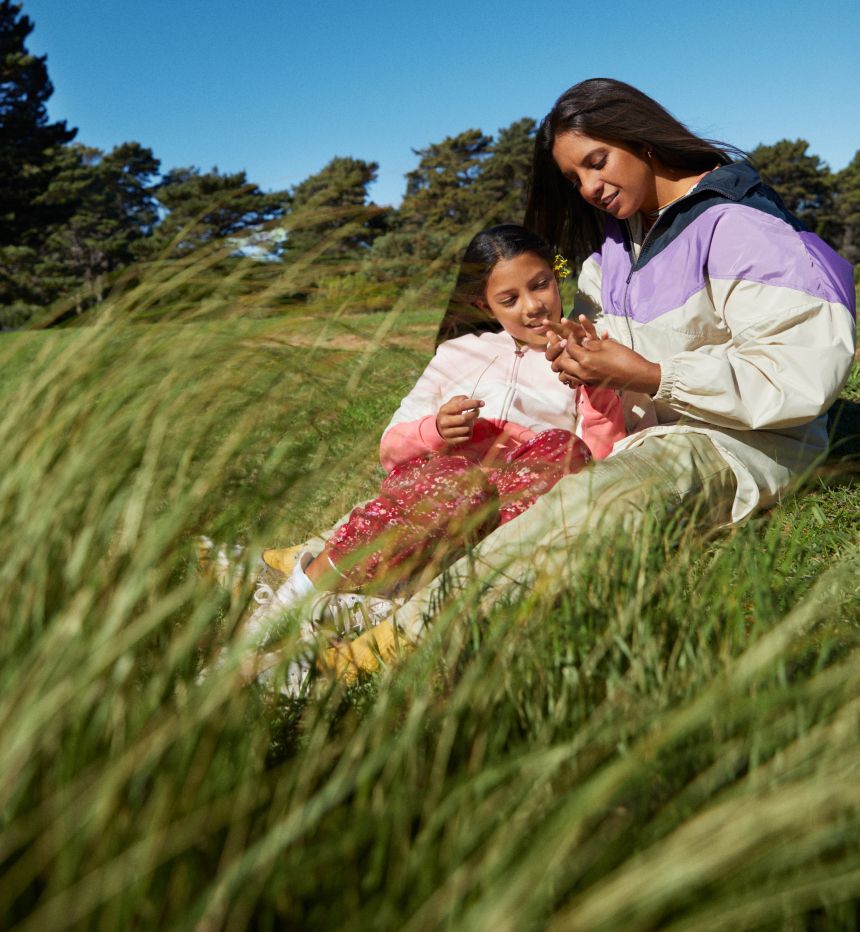 Woman and girl sitting in field of grass