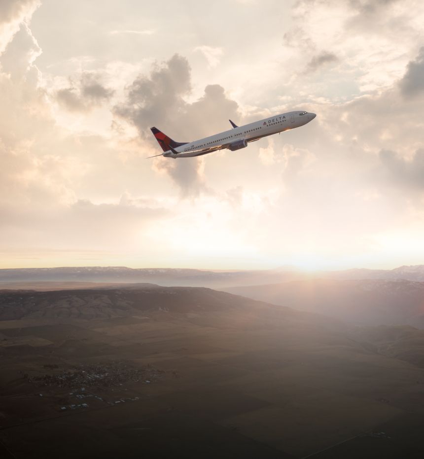 Delta aircraft climbing after take off with clouds in the background