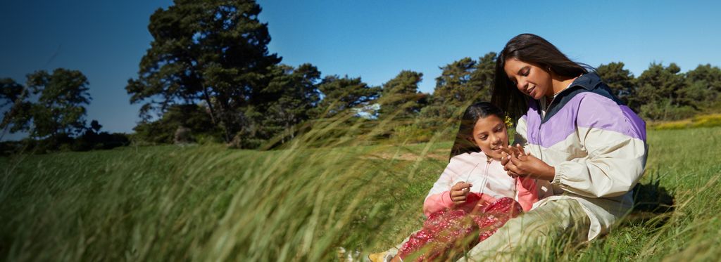 Woman and girl sitting in field of grass