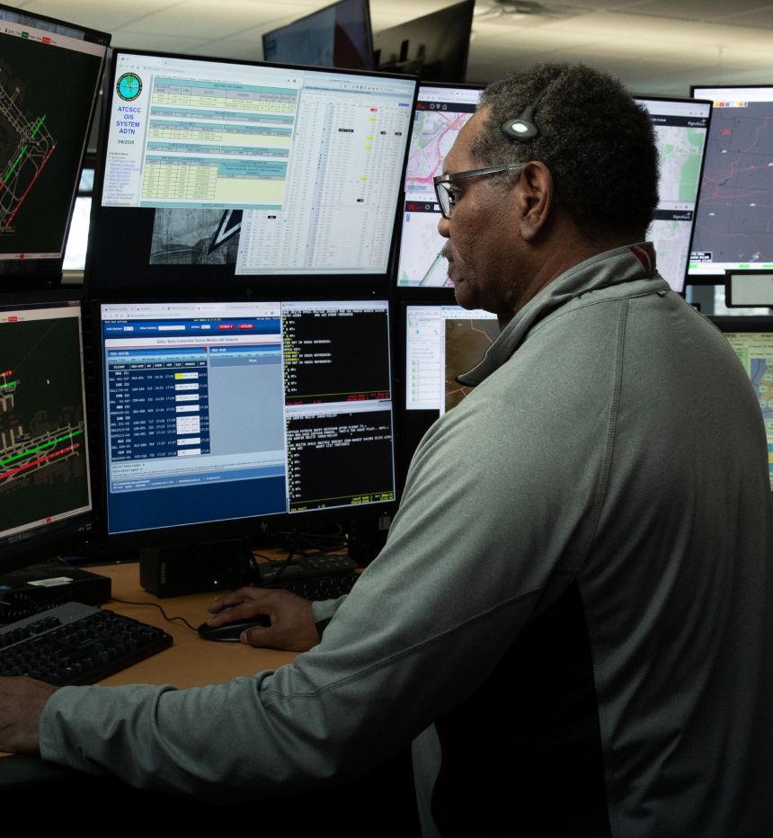 Employee with headset working at desk with multiple computer monitors