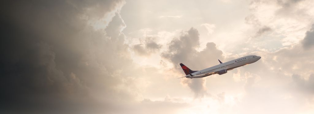 Delta aircraft climbing after take off with clouds in the background
