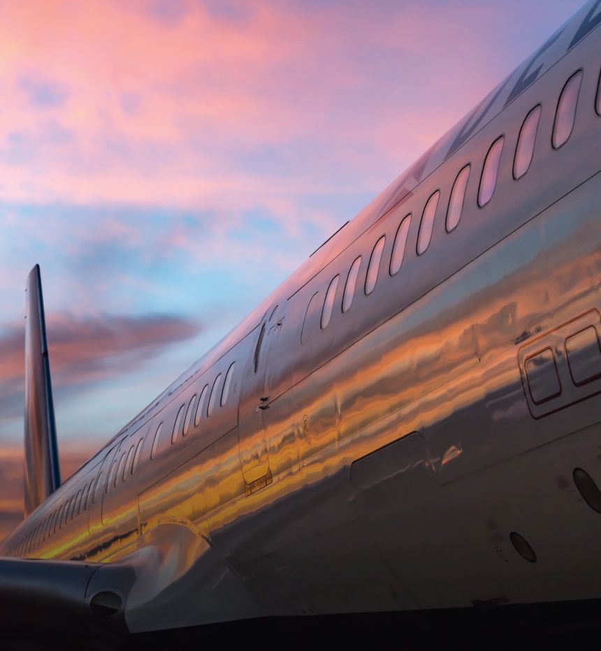 The side of a Delta aircraft looks orange and pink at sunset.