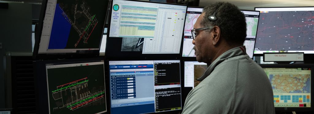 Employee with headset working at desk with multiple computer monitors