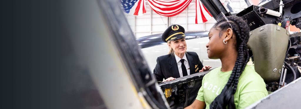 Delta pilot speaking to young girl seated in airplane cockpit