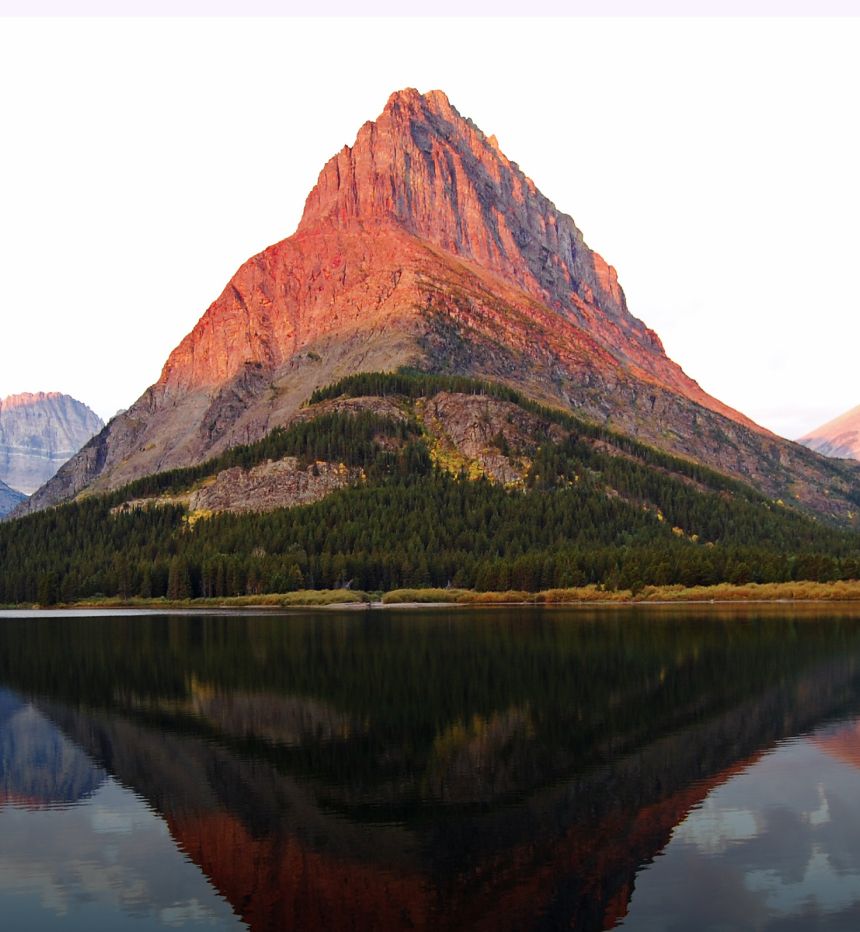 A mountain catches the orange-pink light of the sun