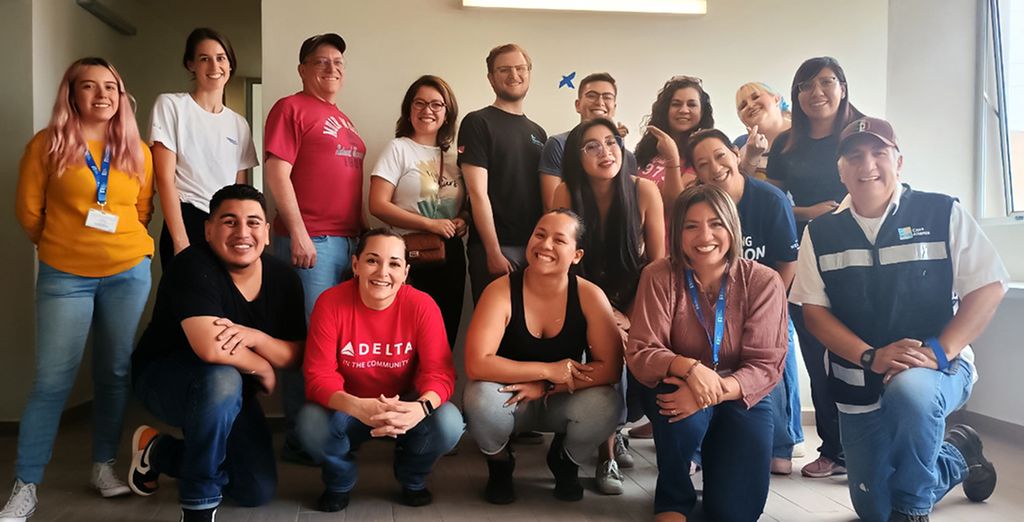 A group of people posing for a photo indoors. There is a logo that reads 'Casa Alianza México' along with an emblem of an eagle.