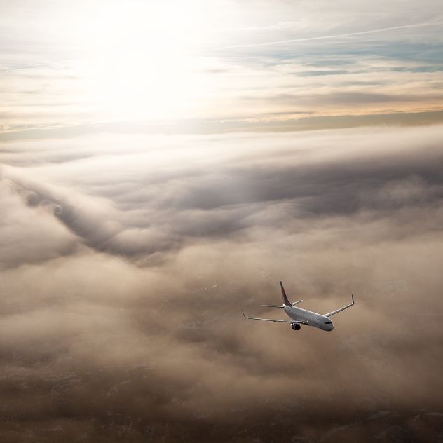 A Delta airplane flying above a mix of light and dark cloud formations.