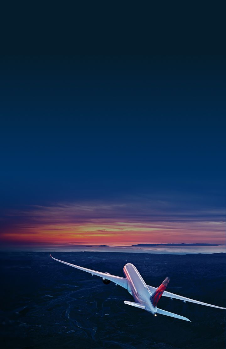 A Delta airplane soars into a colorful sunset, with land and water below, framed by a modern arch design.