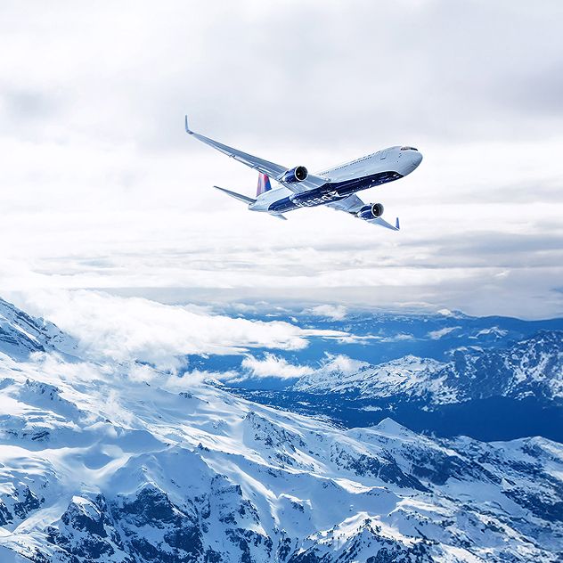 Aircraft with Delta branding on the belly flies beneath a cloudy sky with a snow-covered Mount Rainier in the background.