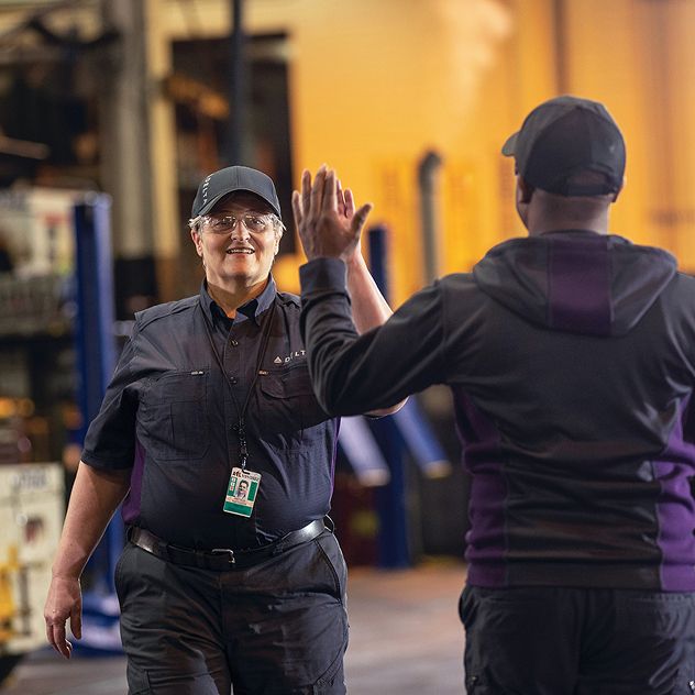 Two Delta employees in uniform giving each other a high-five.