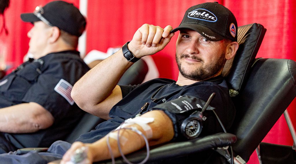 A Delta employee sitting in a chair, donating blood.