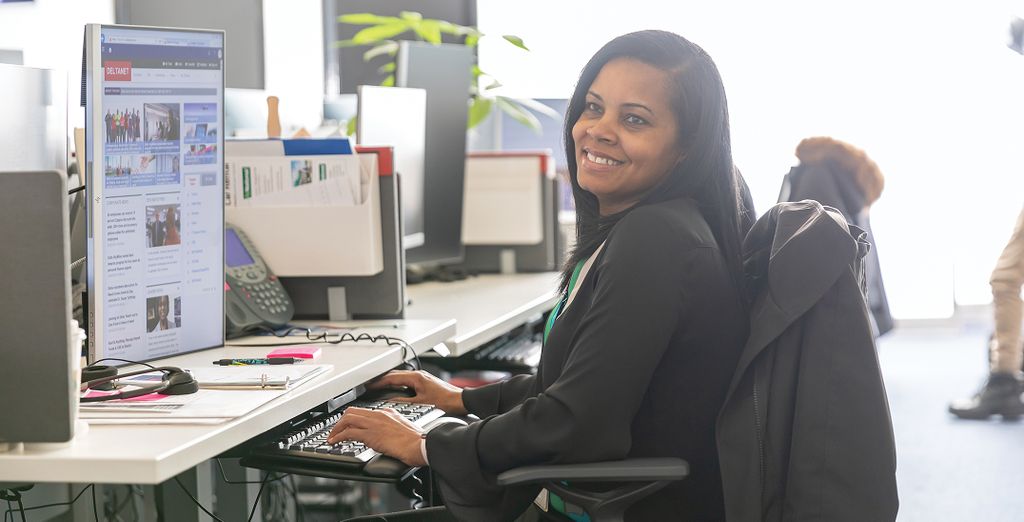 A Delta employee working on a computer at a desk in an office environment.