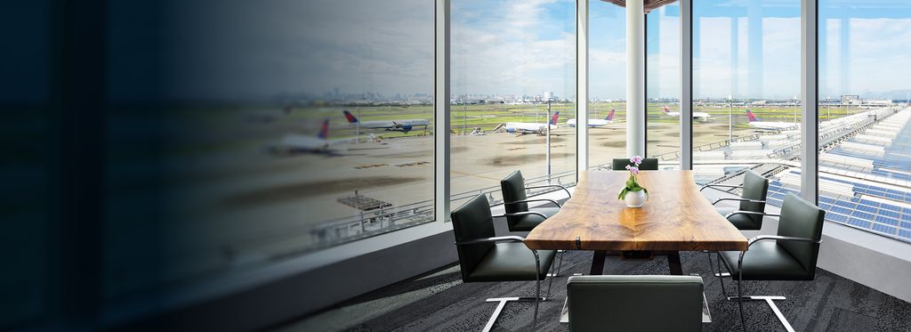 A conference room with a table, chairs, and a view of an airport runway through large windows.