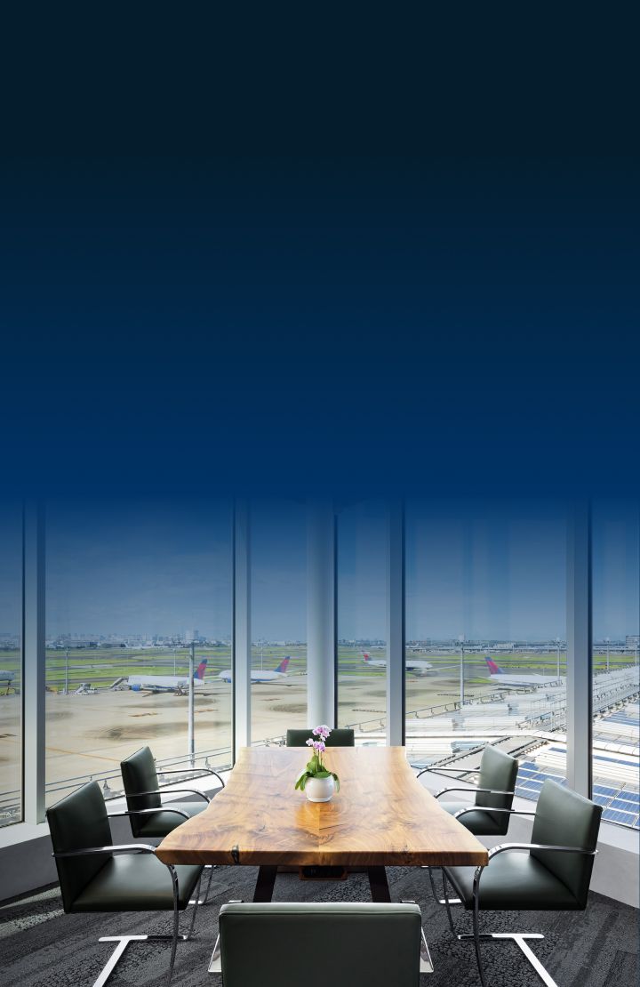 A conference room with a table, chairs, and a view of an airport runway through large windows.
