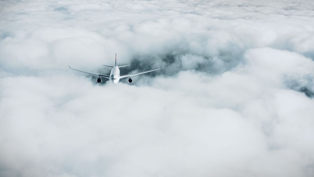 A Delta airplane is flying through a thick layer of clouds. The scene captures the vast expanse of white clouds surrounding the plane, creating a sense of altitude and isolation.