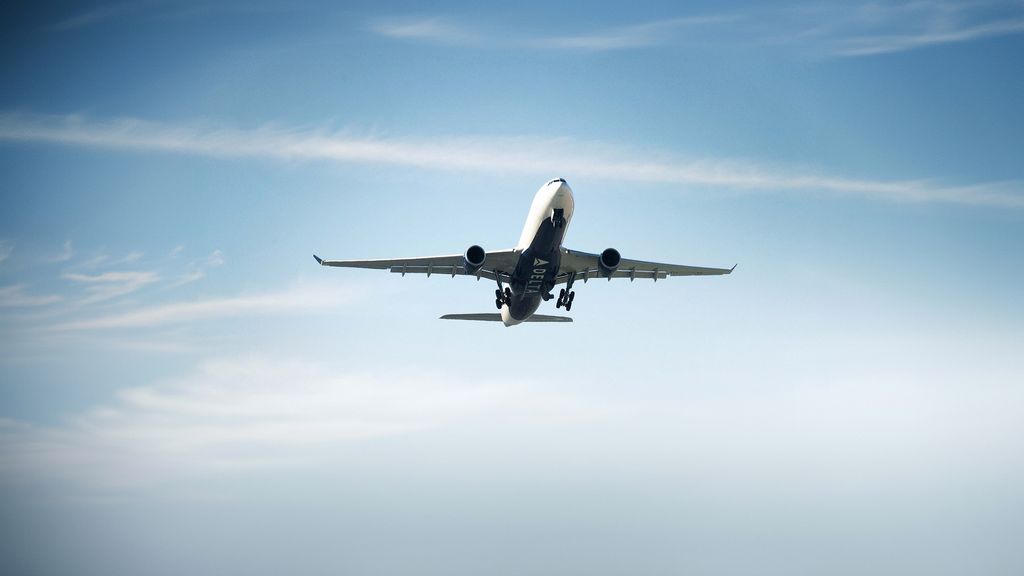 A Delta airplane flying over rocky mountain terrain