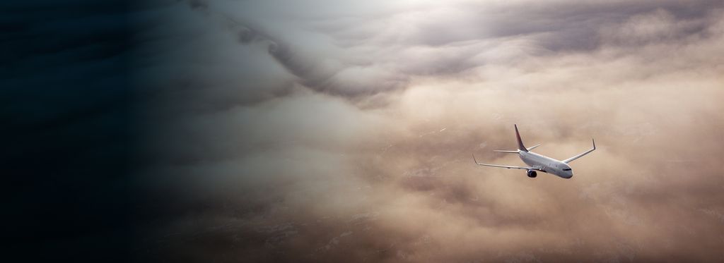A Delta airplane flying above a mix of light and dark cloud formations.