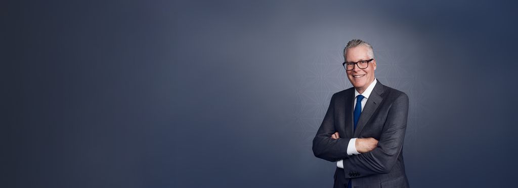 A professional portrait of a Delta Airlines CES wearing a dark suit, white shirt, and blue tie against a gray patterned background. To the left, text reads “Ed Bastian, Chief Executive Officer, Delta Air Lines,” with his stylized signature above the name.