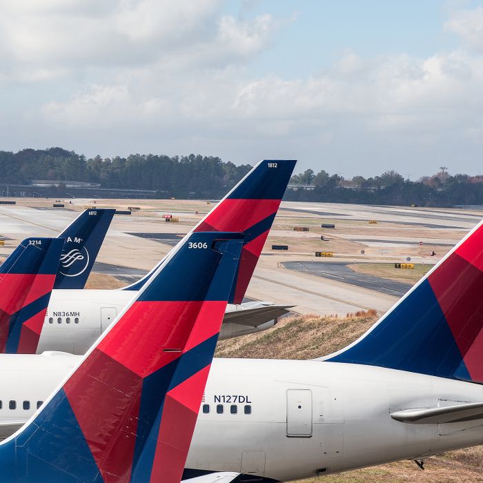 Multiple Delta aircraft lined up on the airport tarmac, showing tail sections with the red and blue Delta widget logo visible.