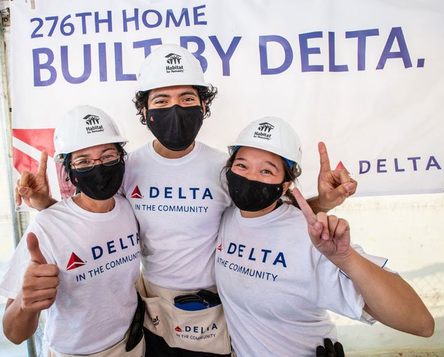 Three volunteers wearing Habitat for Humanity helmets and 